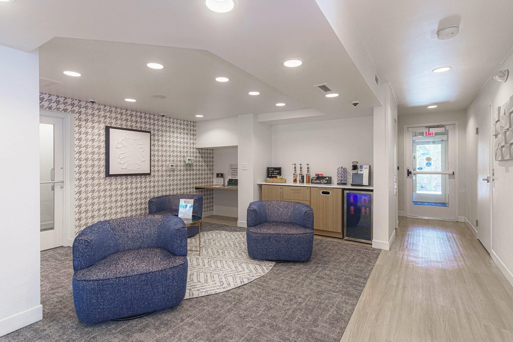a lobby with two chairs and a kitchen in the background